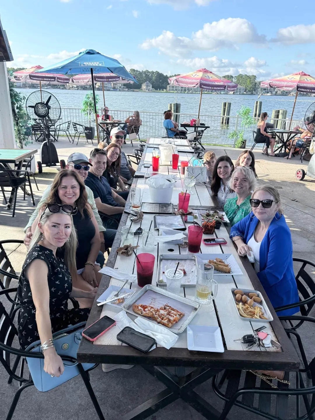 Members gathered around a patio table enjoying a meal together by the water