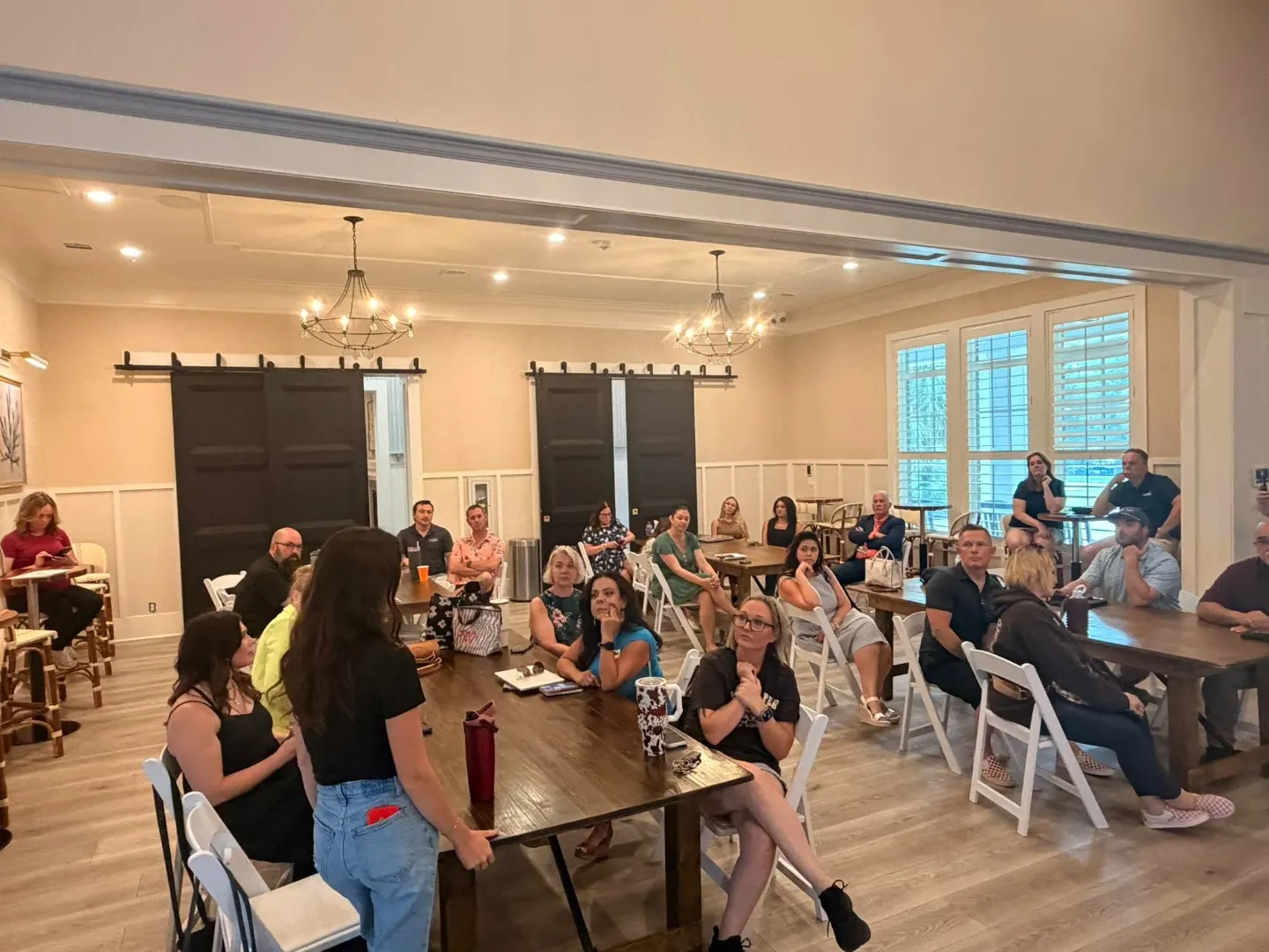 Group seated at long tables during a networking meeting while a member presents